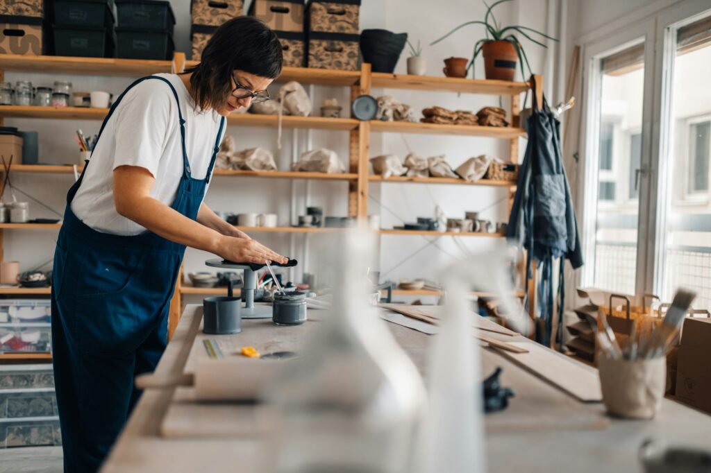 A female artisan preparing surface for clay modeling at pottery workshop.